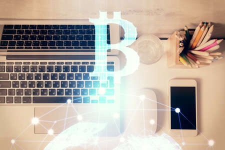 Blockchain theme hologram drawings over computer on the desktop background. Top view. Multi...