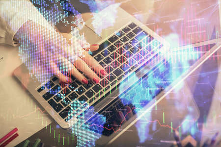 Double exposure of woman hands typing on computer and financial graph hologram drawing. Stock market...