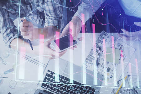 Double exposure of forex graph drawing and man and woman working together holding and using a mobile...