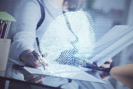Blue fingerprint hologram over woman's hands taking notes background. Concept of protection. Double exposureの写真素材