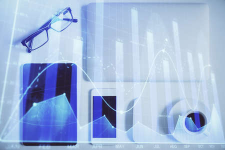 Double exposure of forex chart hologram over desktop with phone. Top view. Mobile trade platform...