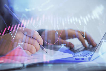 Double exposure of businesswoman hands typing on computer and forex chart hologram drawing....
