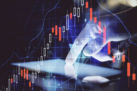 Double exposure of man's hands holding and using a digital device and forex graph drawing. Financial...