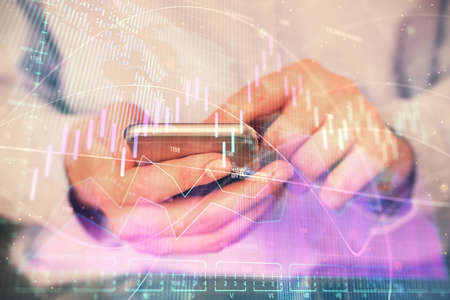 Multi exposure of man's hands holding and using a digital phone and forex graph drawing. Financial...