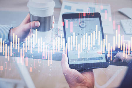 Double exposure of man's hands holding and using a phone and financial chart drawing. Market...