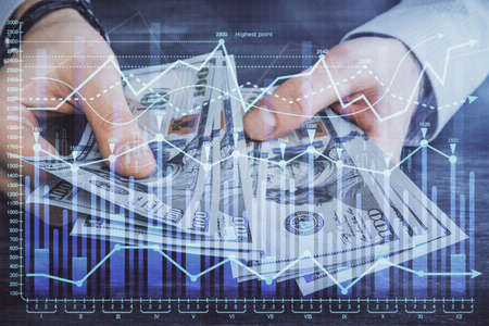 Multi exposure of financial graph drawing hologram and USA dollars bills and man hands. Analysis...