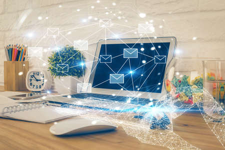 Desktop computer background in office and flying envelops hologram drawing. Double exposure....
