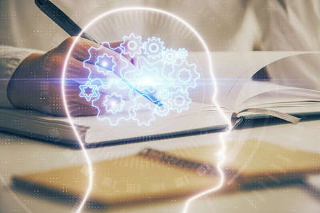 Double exposure of woman's writing hand on background with brain hologram. Concept of brainstorming.