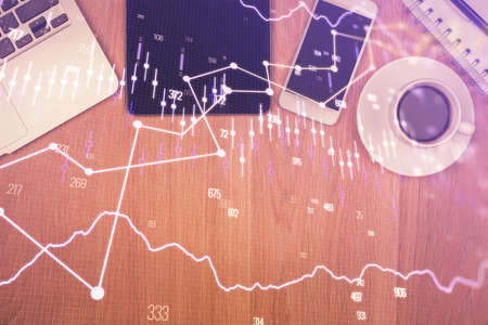 Double exposure of financial chart hologram over desktop with phone. Top view. Mobile trade platform...