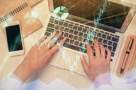 Double exposure of woman hands working on computer and forex graph hologram drawing. Top View....