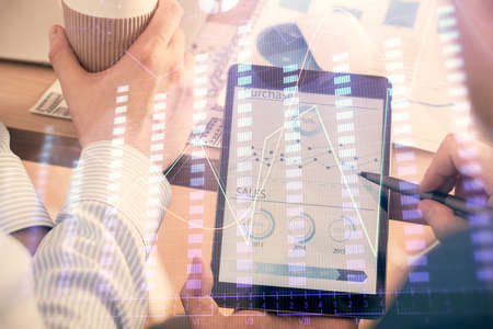 Double exposure of man's hands holding and using a phone and financial chart drawing. Market...