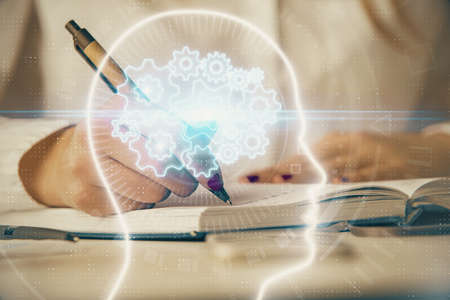 Double exposure of woman's writing hand on background with brain hologram. Concept of brainstorming.