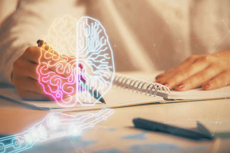 Double exposure of woman's writing hand on background with brain hologram. Concept of brainstorming.