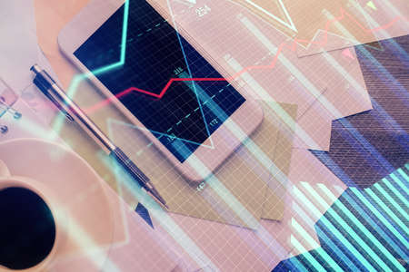 Multi exposure of forex graph hologram over desktop with phone. Top view. Mobile trade platform...