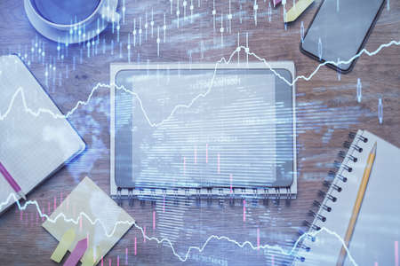 Double exposure of forex chart hologram over desktop with phone. Top view. Mobile trade platform...