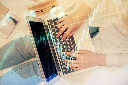 Double exposure of woman hands working on computer and forex graph hologram drawing. Top View....