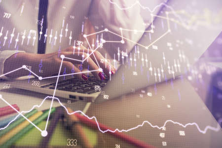 Double exposure of woman hands typing on computer and financial graph hologram drawing. Stock market...