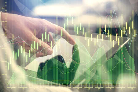 Multi exposure of man's hands holding and using a phone and financial chart drawing. Market analysis...