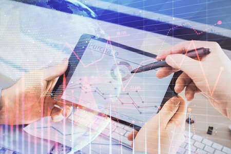 Double exposure of man's hands holding and using a phone and financial chart drawing. Market...