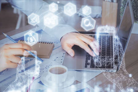Technology theme hologram with man working on computer on background. High tech concept. Multi...