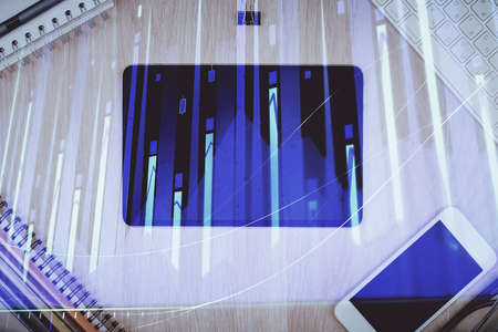 Double exposure of forex graph hologram over desktop with phone. Top view. Mobile trade platform...