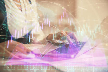 Double exposure of businesswoman hands typing on computer and forex graph hologram drawing....