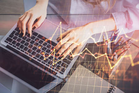 Double exposure of woman hands typing on computer and forex chart hologram drawing. Stock market...
