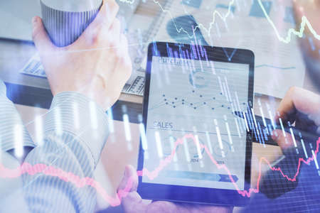 Double exposure of man's hands holding and using a phone and financial chart drawing. Market...