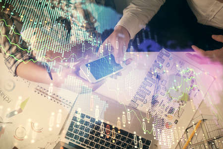 Double exposure of forex graph drawing and man and woman working together holding and using a mobile...