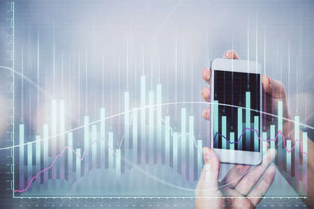 Double exposure of forex graph sketch hologram and woman holding and using a mobile device. Stock...