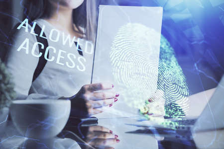 Blue fingerprint hologram over woman's hands taking notes background. Concept of protection. Double...