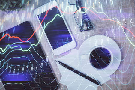 Double exposure of forex chart hologram over desktop with phone. Top view. Mobile trade platform...