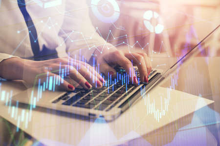 Multi exposure of woman hands typing on computer and financial graph hologram drawing. Stock market...