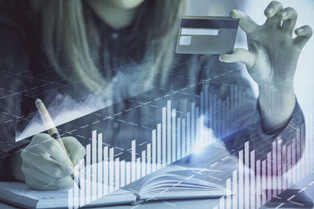 Double exposure of woman on-line shopping holding a credit card and financial graph drawing. Stock market E-commerce concept.の写真素材