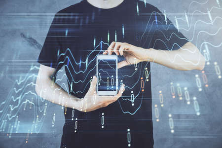 Double exposure of man's hands holding and using a digital device and forex graph drawing. Financial...