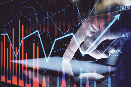 Double exposure of man's hands holding and using a digital device and forex graph drawing. Financial...