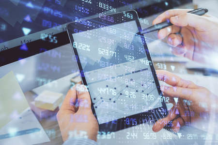 Double exposure of man's hands holding and using a phone and financial chart drawing. Market...