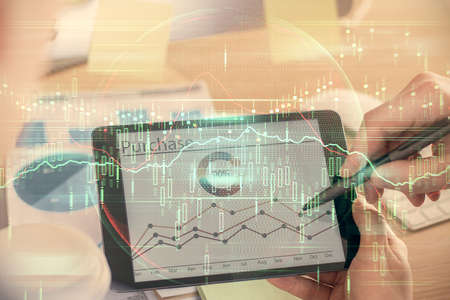 Double exposure of man's hands holding and using a phone and financial chart drawing. Market...