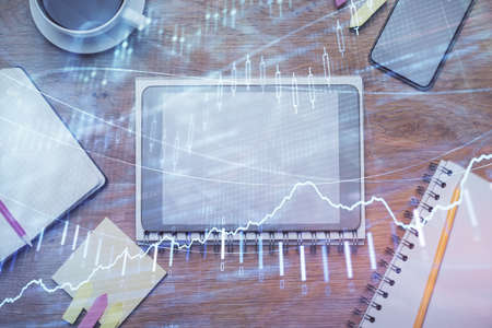 Double exposure of forex chart hologram over desktop with phone. Top view. Mobile trade platform...