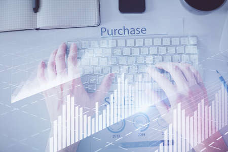 Double exposure of man's hands typing over laptop keyboard and forex chart hologram drawing. Top...