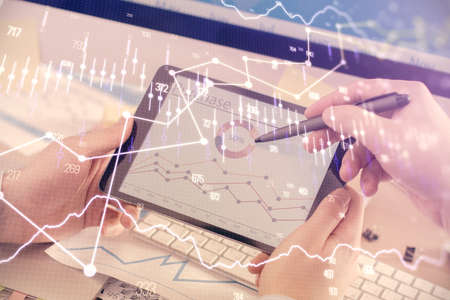 Double exposure of man's hands holding and using a phone and financial chart drawing. Market...