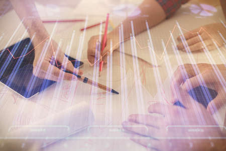 Double exposure of forex graph drawing and man and woman working together holding and using a mobile device. Trade concept.の写真素材