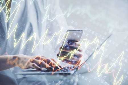 Double exposure of financial graph sketch hologram and woman holding and using a mobile device....