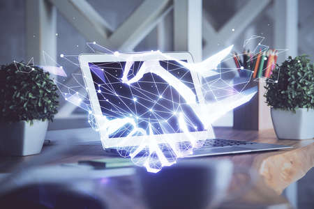 Desktop computer background in office and handshake hologram drawing. Double exposure. Pertnership...