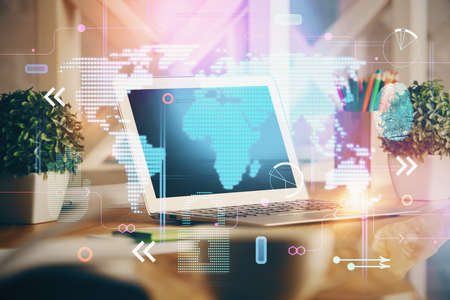 Double exposure of desktop with computer and world map hologram. International data network concept.