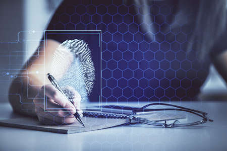 Blue fingerprint hologram over woman's hands taking notes background. Concept of protection. Double exposureの写真素材
