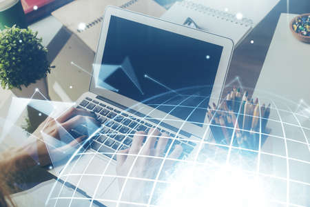 Double exposure of world map hologram with man working on computer on background. Concept of...