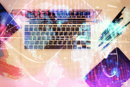 Business theme hologram drawings over computer on the desktop background. Top view. Multi exposure....