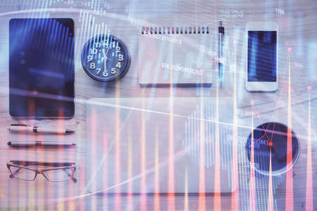 Double exposure of forex graph hologram over desktop with phone. Top view. Mobile trade platform...