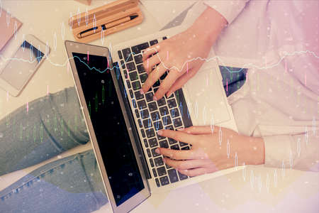 Double exposure of woman hands working on computer and forex graph hologram drawing. Top View....